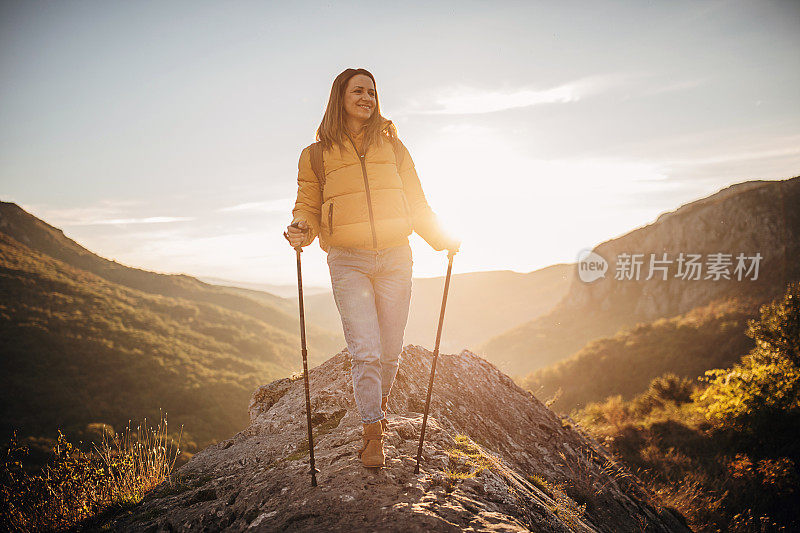 在一个阳光明媚的秋日，一名年轻女子在山里徒步旅行