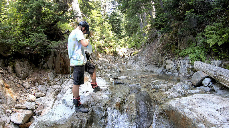 女山地自行车填满水瓶在高山溪流