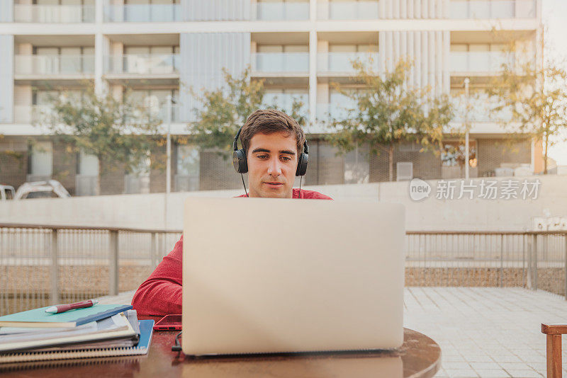 微笑的大学生在户外使用笔记本电脑的肖像