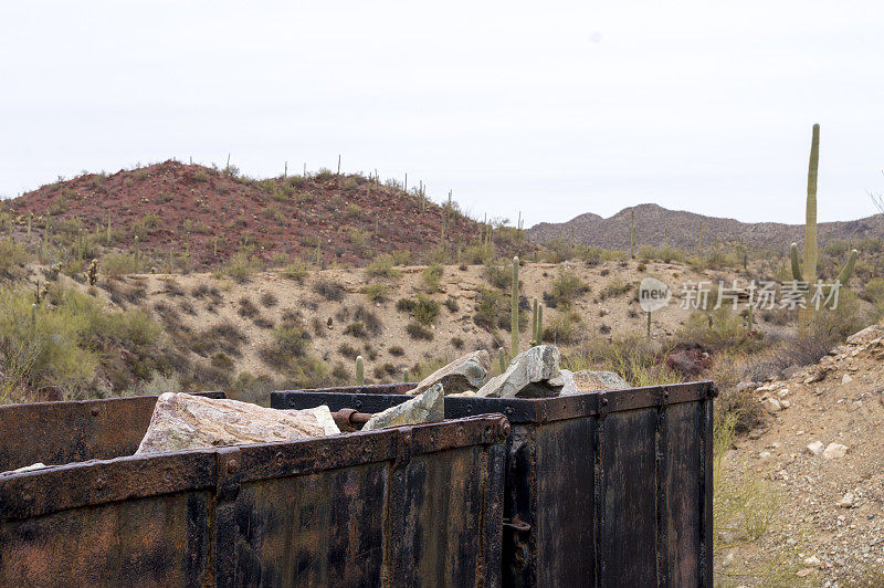 在萨瓜罗国家公园附近的沙漠场景前，生锈的矿车装载着矿石