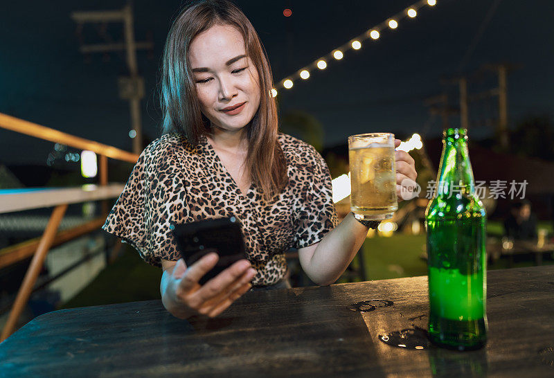 独自坐在户外餐厅喝啤酒的女人