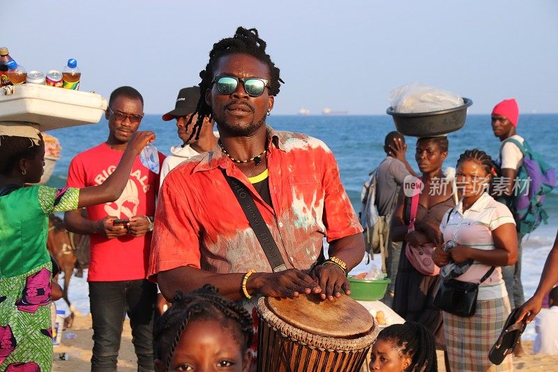 下午晚些时候，在西非多哥Lomé的海滩上，音乐家拿着鼓为观众表演。