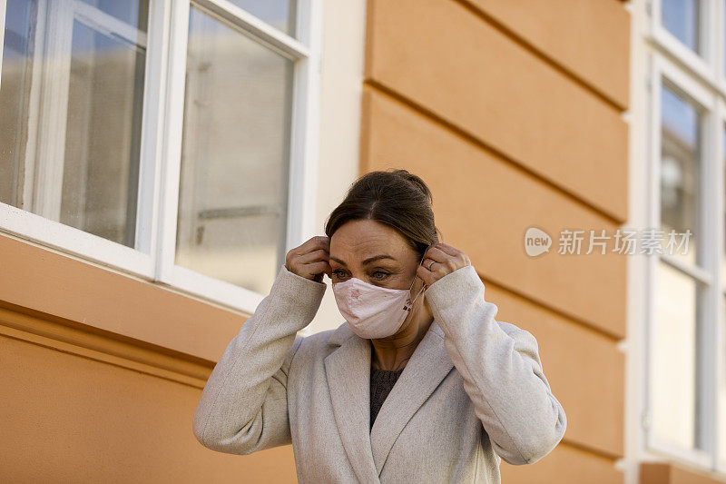 成熟的女人正在调整她所戴的保护面罩