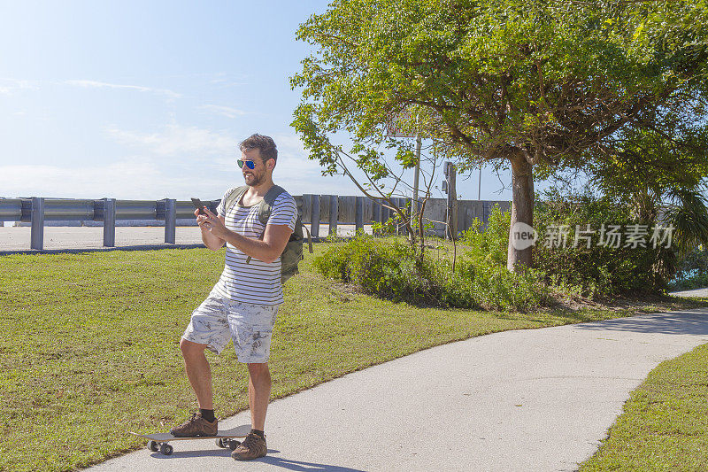美国佛罗里达州基韦斯特，一个炎热的夏日，一名年轻人正在用智能手机发短信