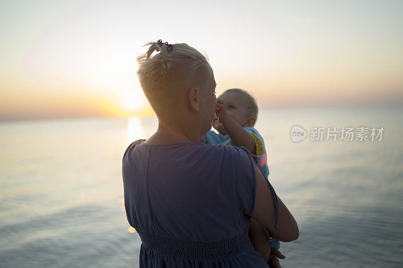母亲和儿子在海滩上欣赏日落