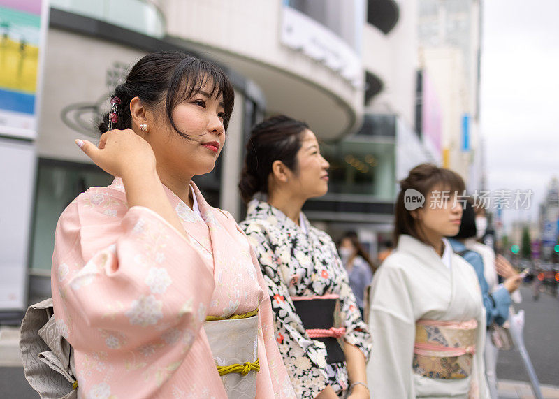 穿着和服的女性朋友站在城市的街道上