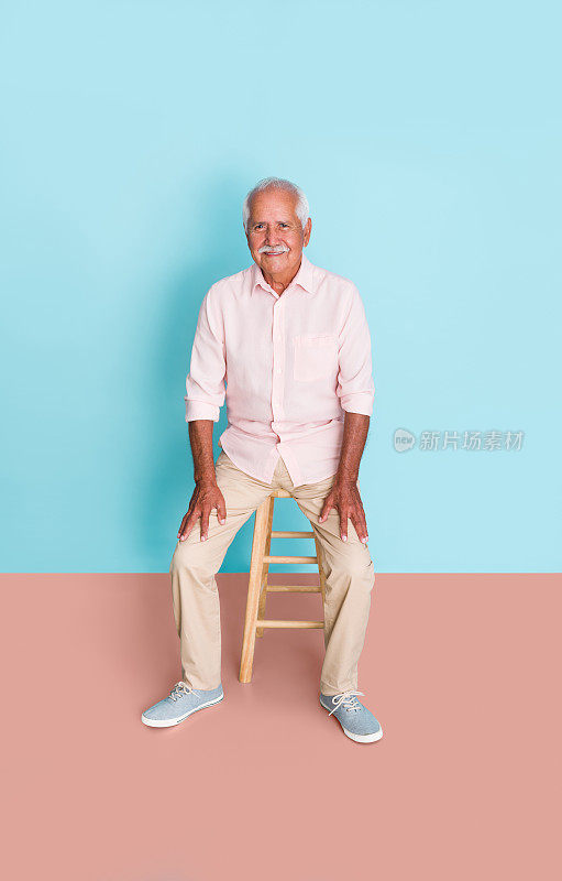 快乐的老人坐在凳子上，对着镜头微笑