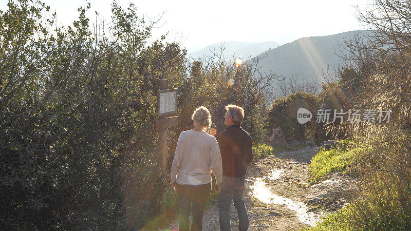 成熟的远足夫妇接近步道标志在日出