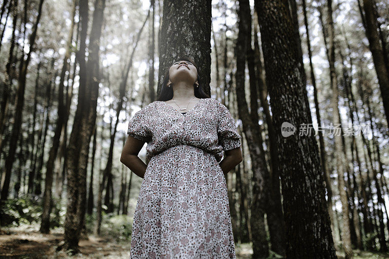 森林里一个年轻的女人靠在一棵树上