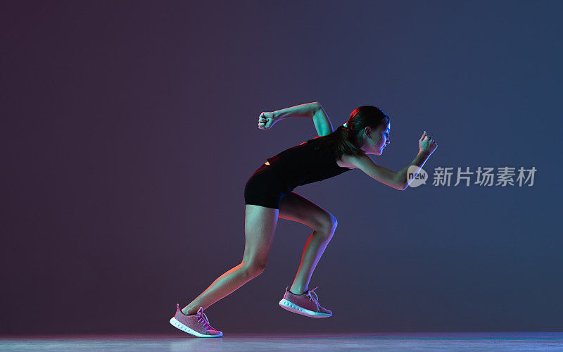 全长侧视图肖像的女孩，职业运动员，跑步者训练孤立的梯度蓝色紫色背景在霓虹灯