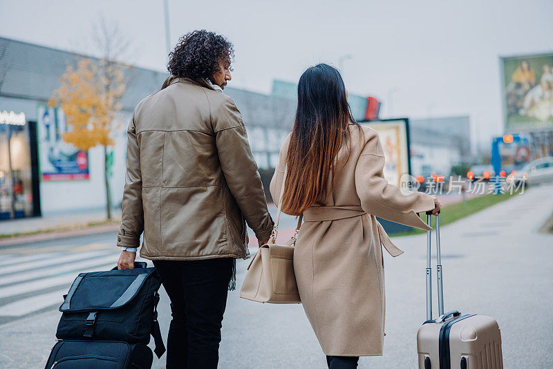 商人和女商人在商务旅行中走在人行道上，带着手提行李