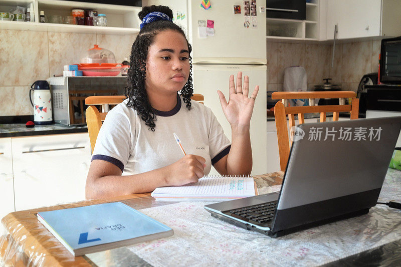 一个十几岁的女孩在家里用笔记本电脑学习