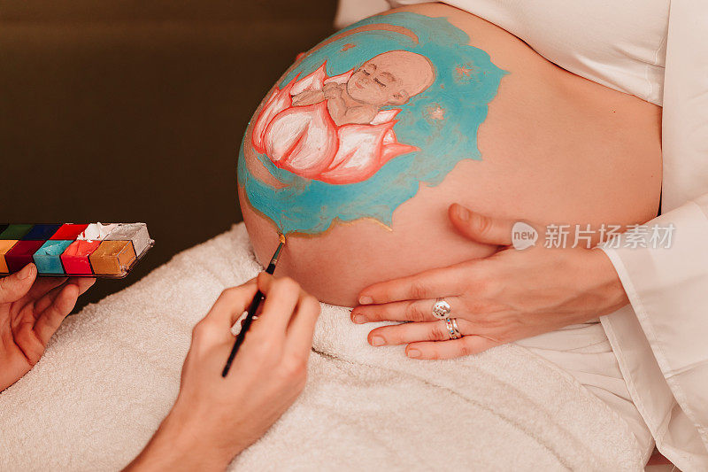 准爸爸温柔地画着他深爱的妻子怀孕的肚子，画着一个坐在曼陀罗中心的莲花里的女婴