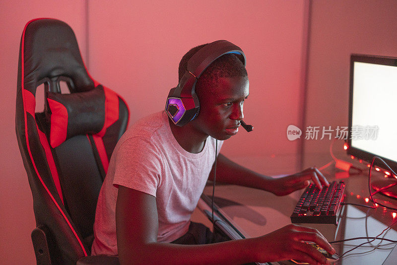 年轻的黑人男性玩家在车站使用台式电脑和笔记本电脑