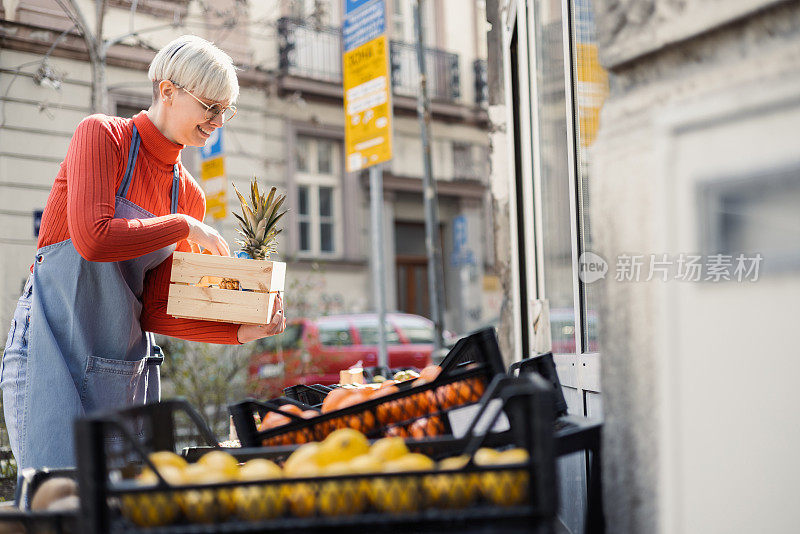 年轻的女售货员正在店里摆放水果