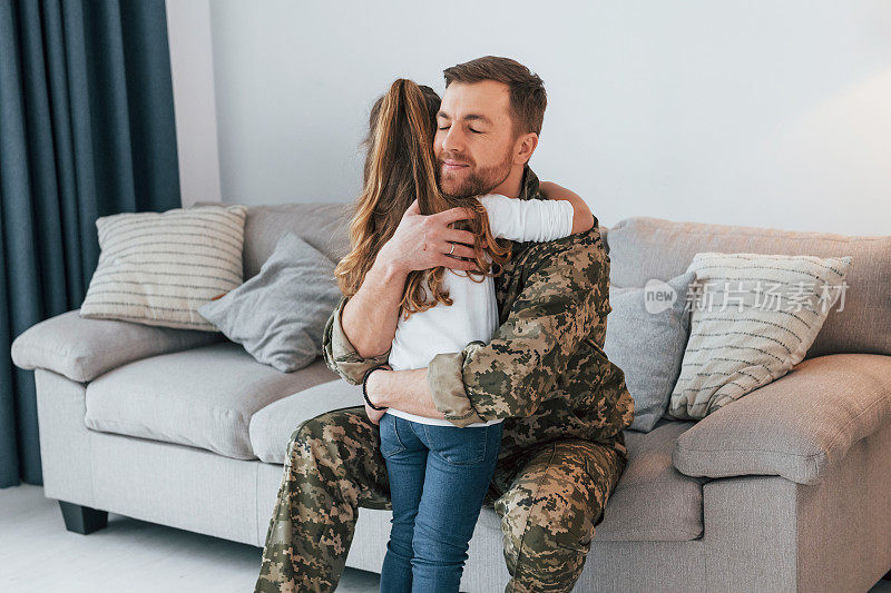 想念你。穿制服的士兵和他的小女儿在家里