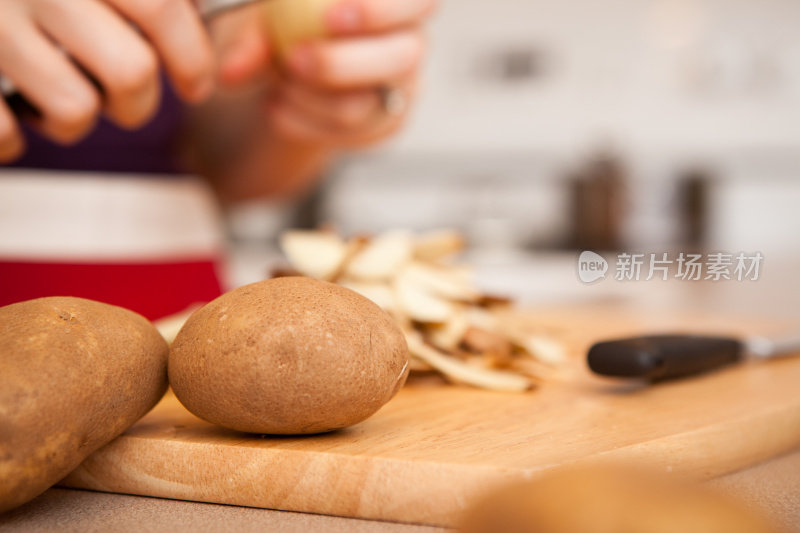 在家厨房削红褐色土豆的女人