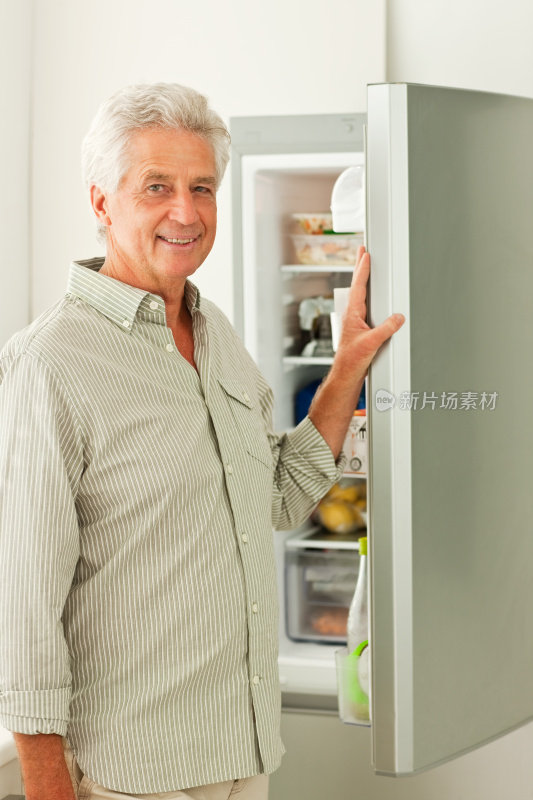 一位老人站在电冰箱前