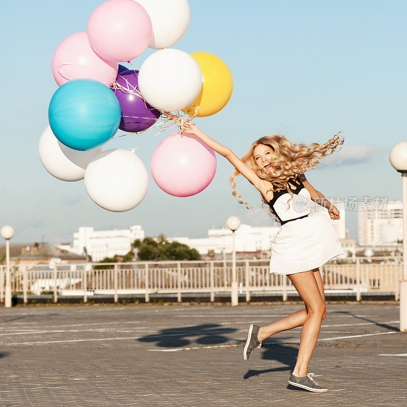 带着彩色乳胶气球的快乐年轻女人