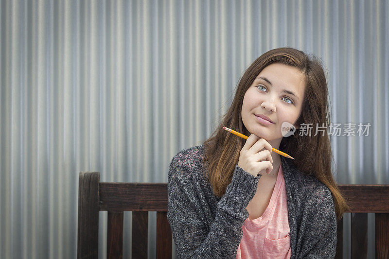 年轻的女学生用铅笔往一边看