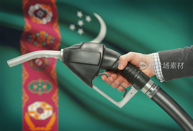 手握燃油泵喷嘴，背景是土库曼斯坦国旗