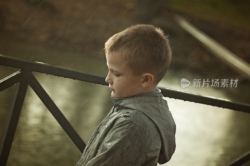 悲伤的男孩站在雨中