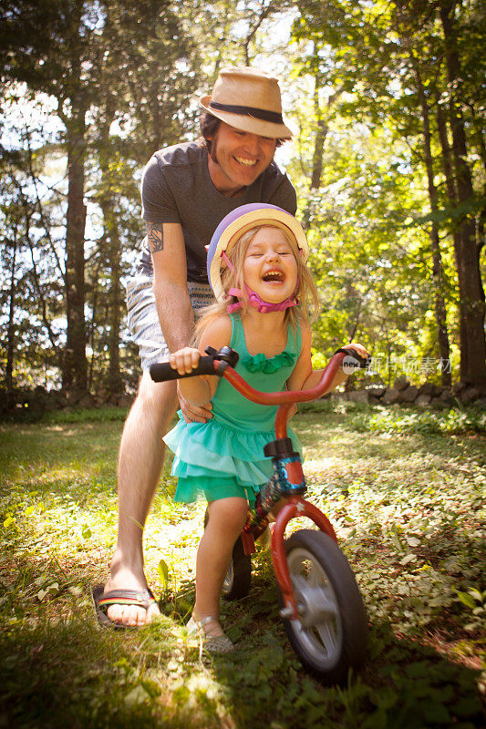 爸爸和女儿在她骑自行车的时候大笑