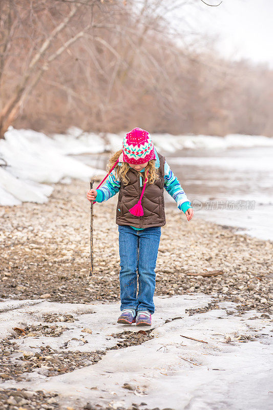 少女在河边的冰上行走