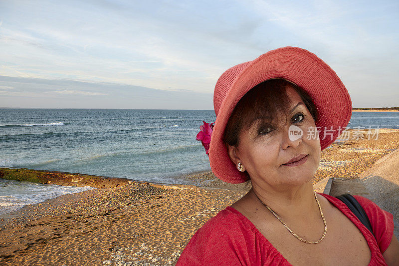 成熟微笑的西班牙妇女在海滩太阳帽