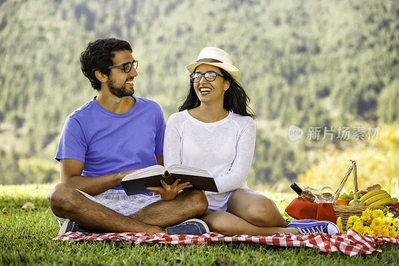 年轻的西班牙裔或拉丁裔夫妇在公园看书