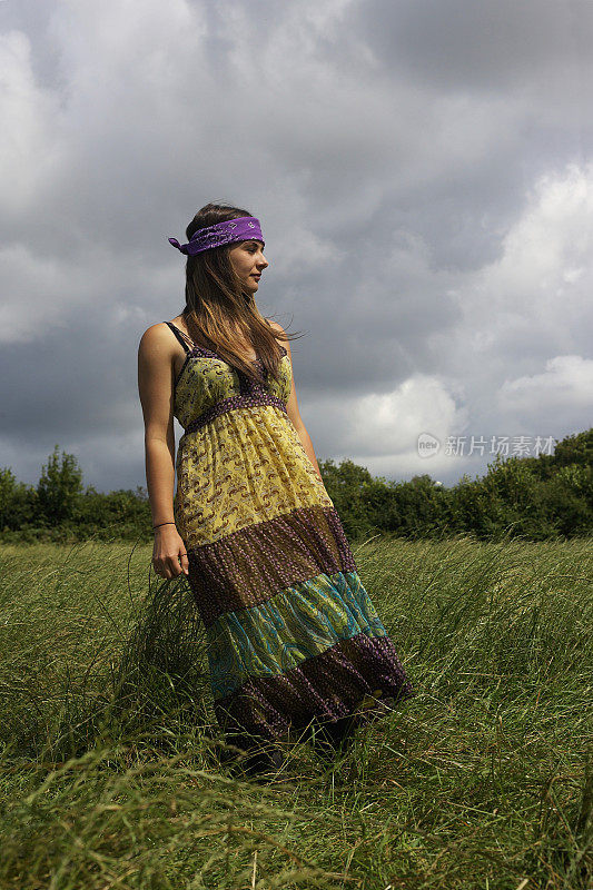 年轻的嬉皮女孩戴着头巾站在田野里