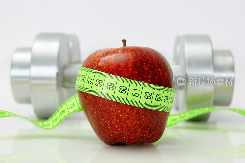 健康生活理念-苹果与卷尺和哑铃。