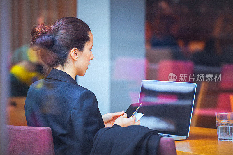 年轻的女商人在咖啡馆使用信用卡进行网上交易