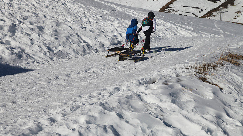 男孩们玩雪橇冬季运动，在瑞士阿尔卑斯山滑雪