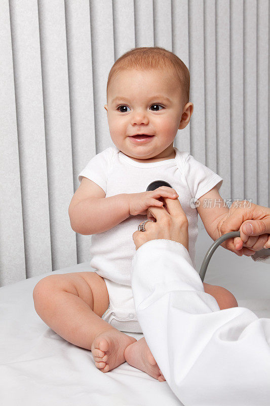 微笑婴儿抱着儿科医生的听诊器
