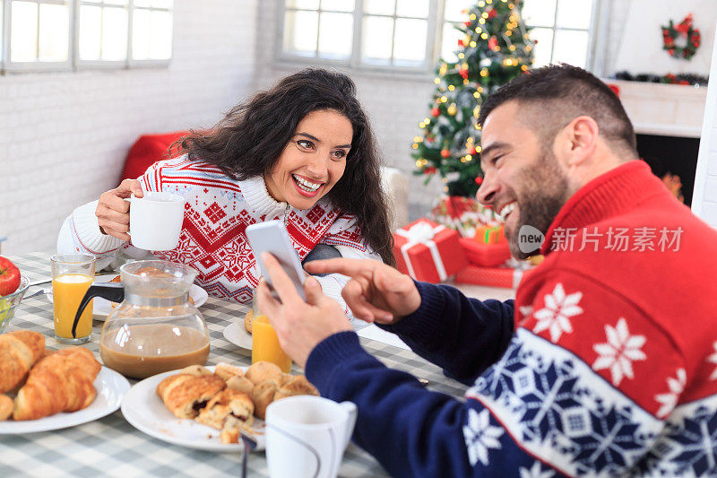 夫妇俩在家里喝咖啡，用智能手机