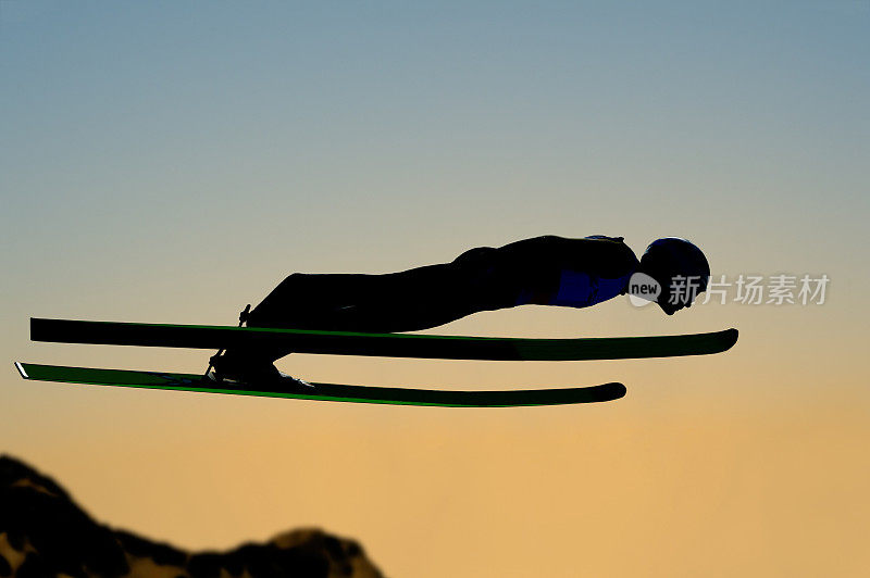 日落时跳台滑雪飞行的剪影