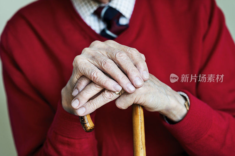 90岁老人双手拄着拐杖。