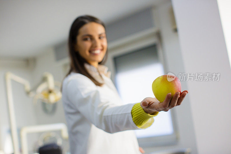 一个女牙医手里拿着一个苹果