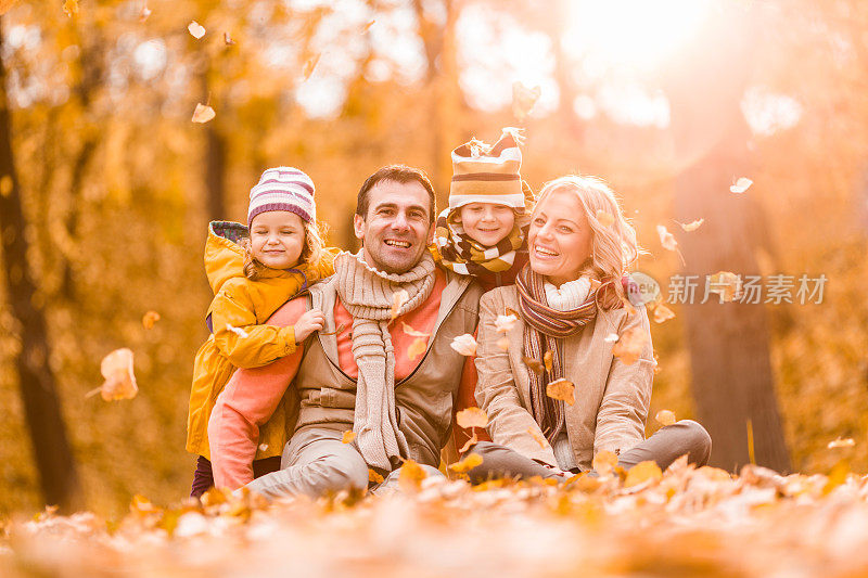 幸福的一家人坐在秋天的公园里享受。