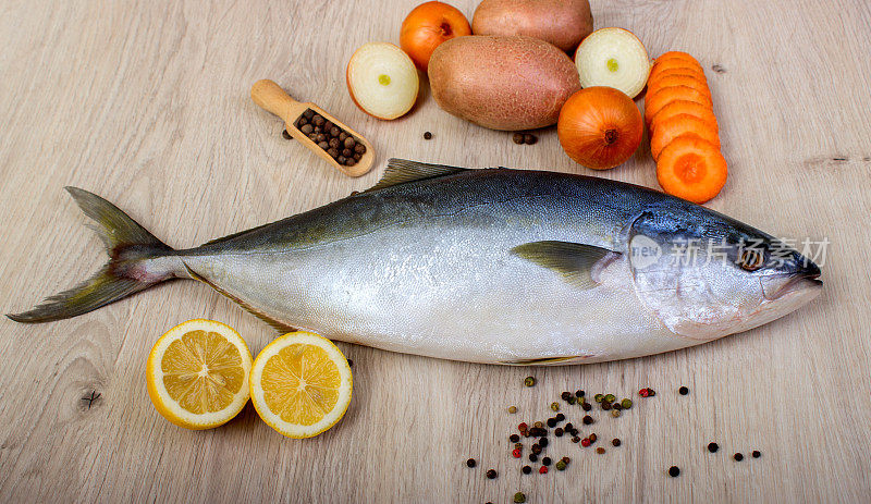 新鲜的鱼与柠檬，欧芹和香料分开放在木板上