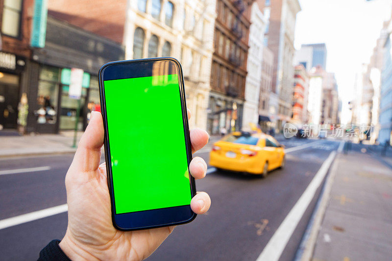 一名男性在曼哈顿街头用绿色屏幕手持智能手机打出租车