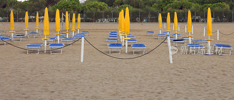 沙滩上有许多紧闭的阳伞