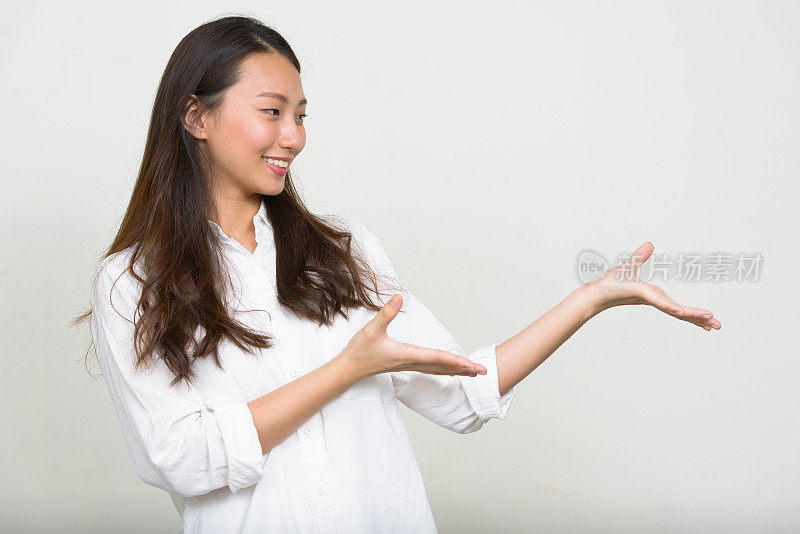 年轻美丽的亚洲女人穿着白色衬衫对抗白色背景