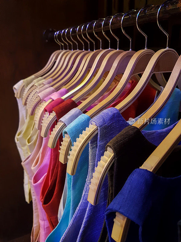 泰国丝绸面料的妇女上衣挂在泰国丝绸商店的架子上，显示出许多色调。