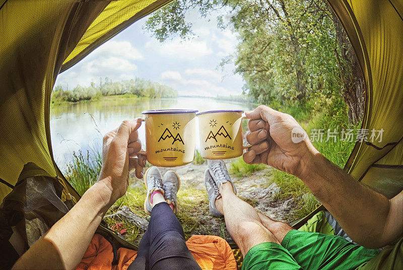 年轻夫妇坐在帐篷里喝茶，看着德斯纳河，乌克兰