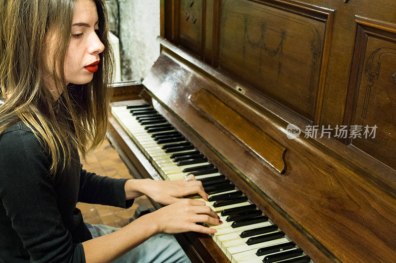 一个年轻女子在弹奏一架老式钢琴，眼睛却在别处看。