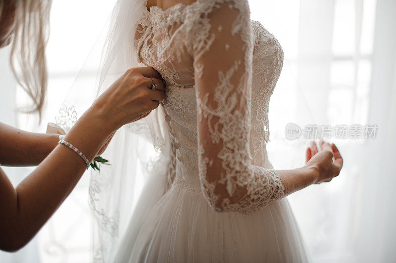 伴娘在新娘的婚纱背面做蝴蝶结