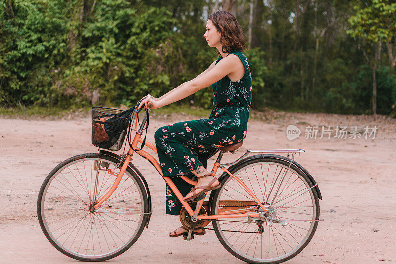 年轻的白人妇女在吴哥窟骑自行车