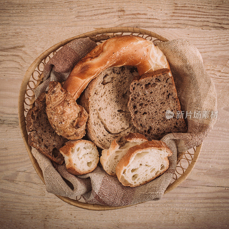 质朴的木桌上放着许多混合的烤面包和面包卷